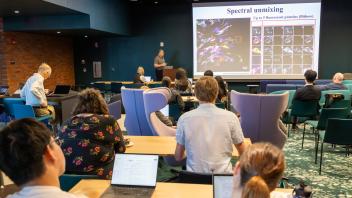 Audience in a lecture hall watching a presenter and scientific slides